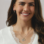 A pair of silver hoop earrings with dangling heart shaped cubic zirconia's.