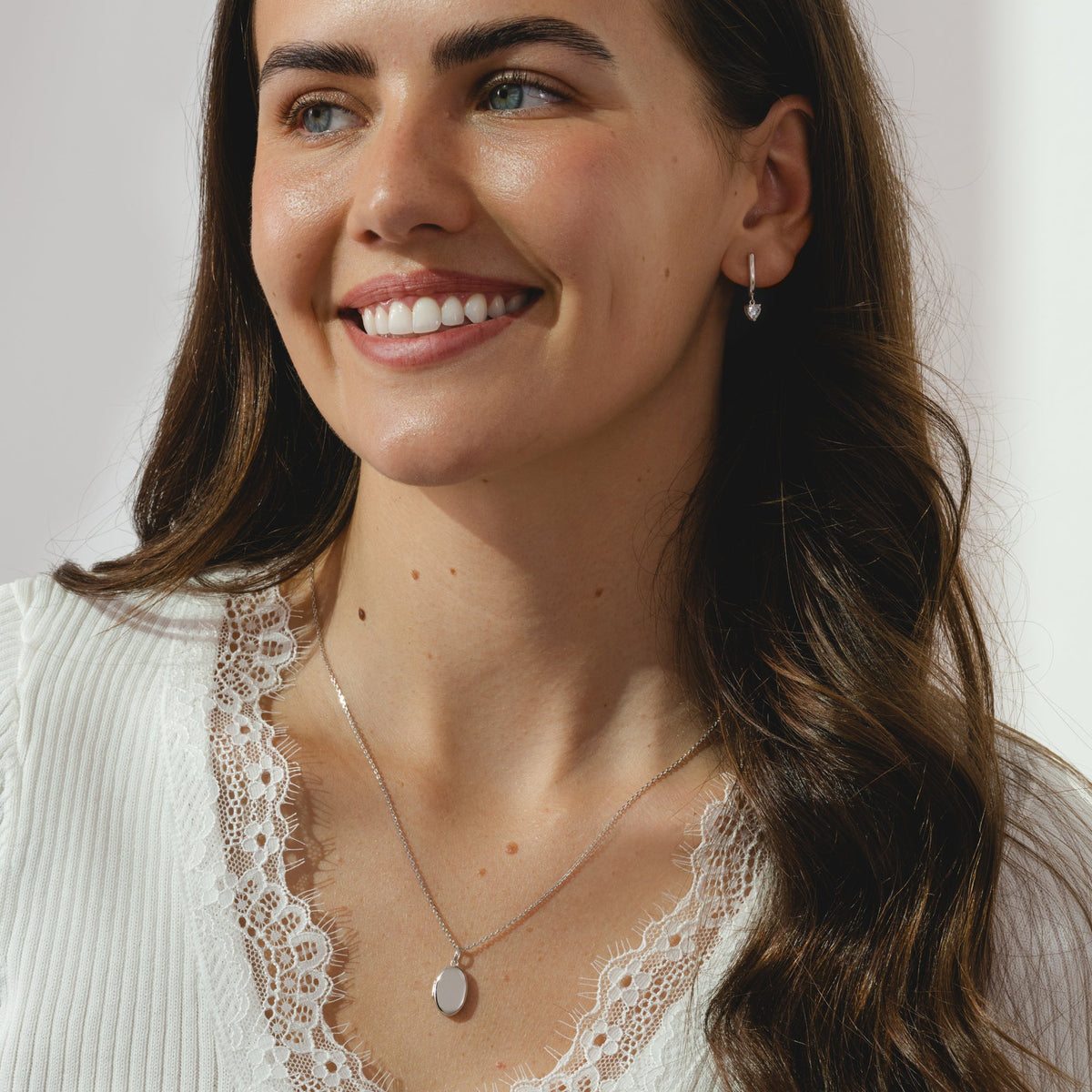 A pair of silver hoop earrings with dangling heart shaped cubic zirconia's.