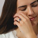 A gold ring with oval blue sapphire ring with surrounding halo diamond