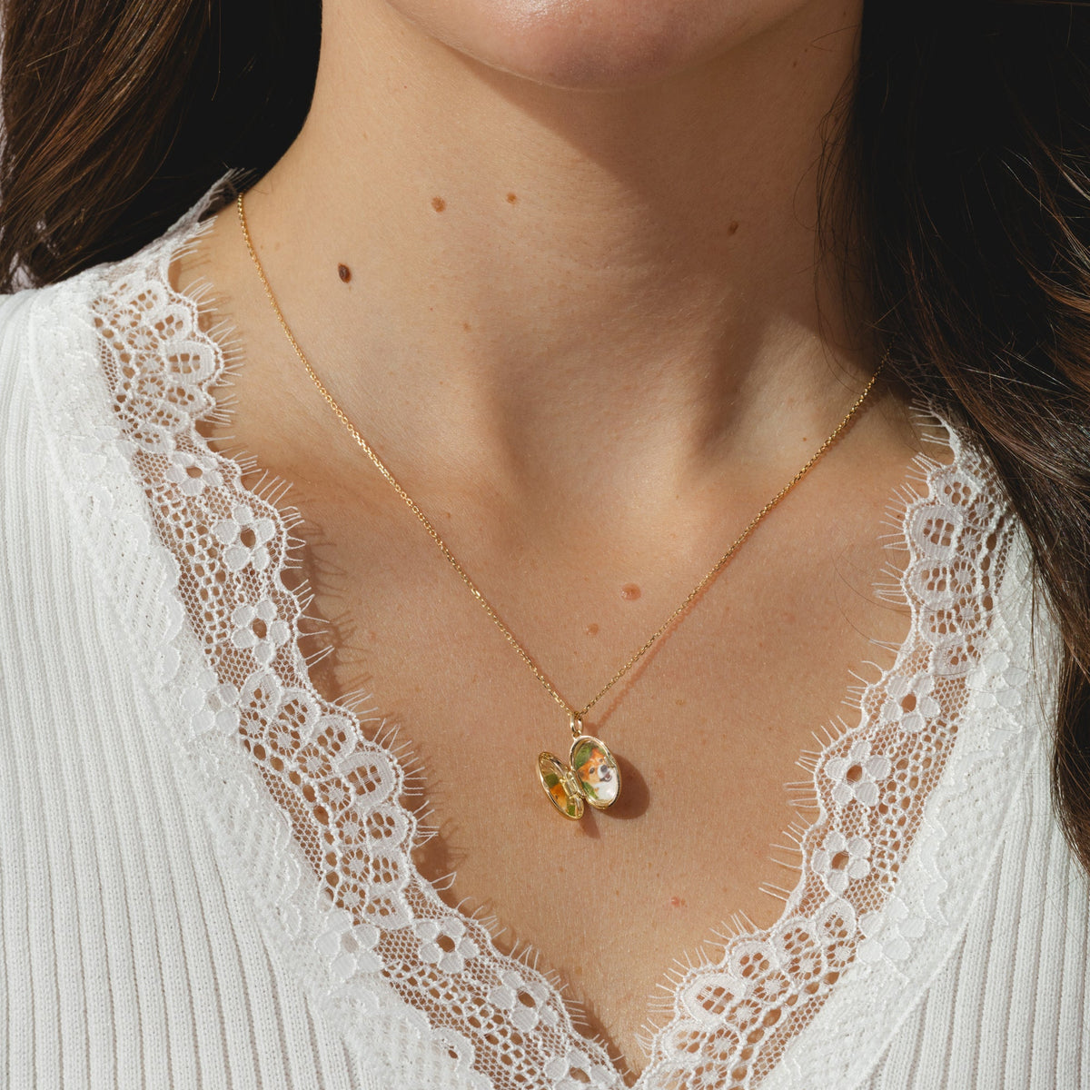 A gold locket pendant necklace on a delicate gold chain.