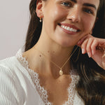 A gold locket pendant necklace on a delicate gold chain.