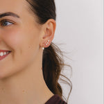 A pair of gold hook earrings with a single round cut diamond in a four prong setting.