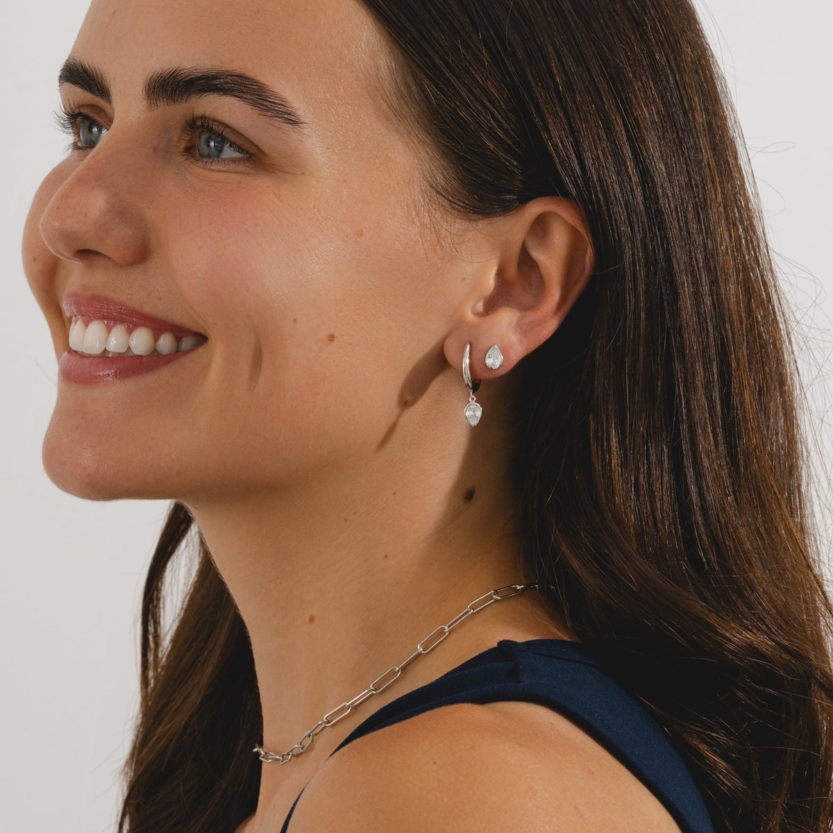 Silver hoop earrings with pear cut cubic zirconia pendants in a silver bezel setting.