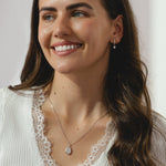 A pair of silver hoop earrings with dangling heart shaped cubic zirconia's.