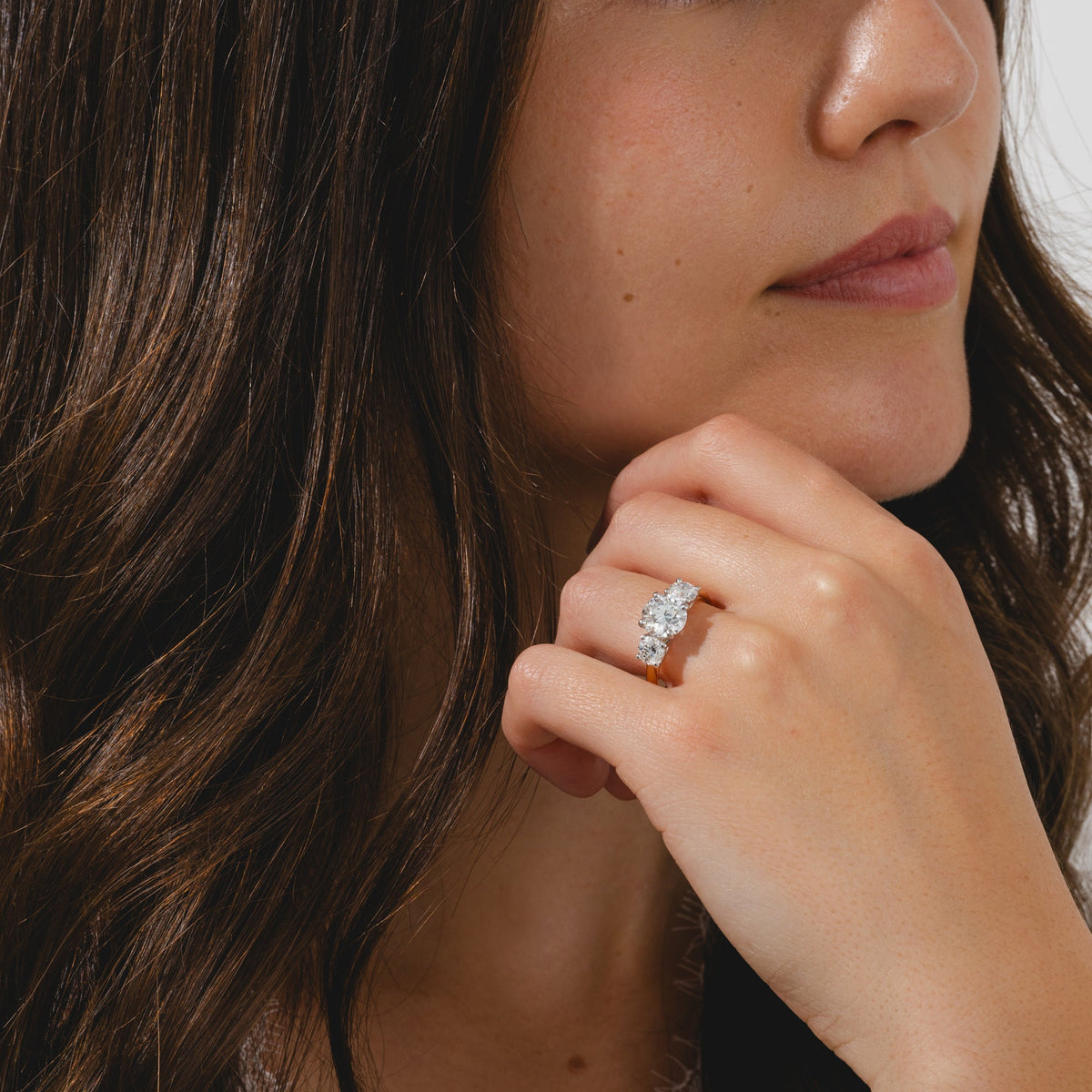 A yellow gold three-stone ring featuring a round cut center diamond flanked by two side diamonds.