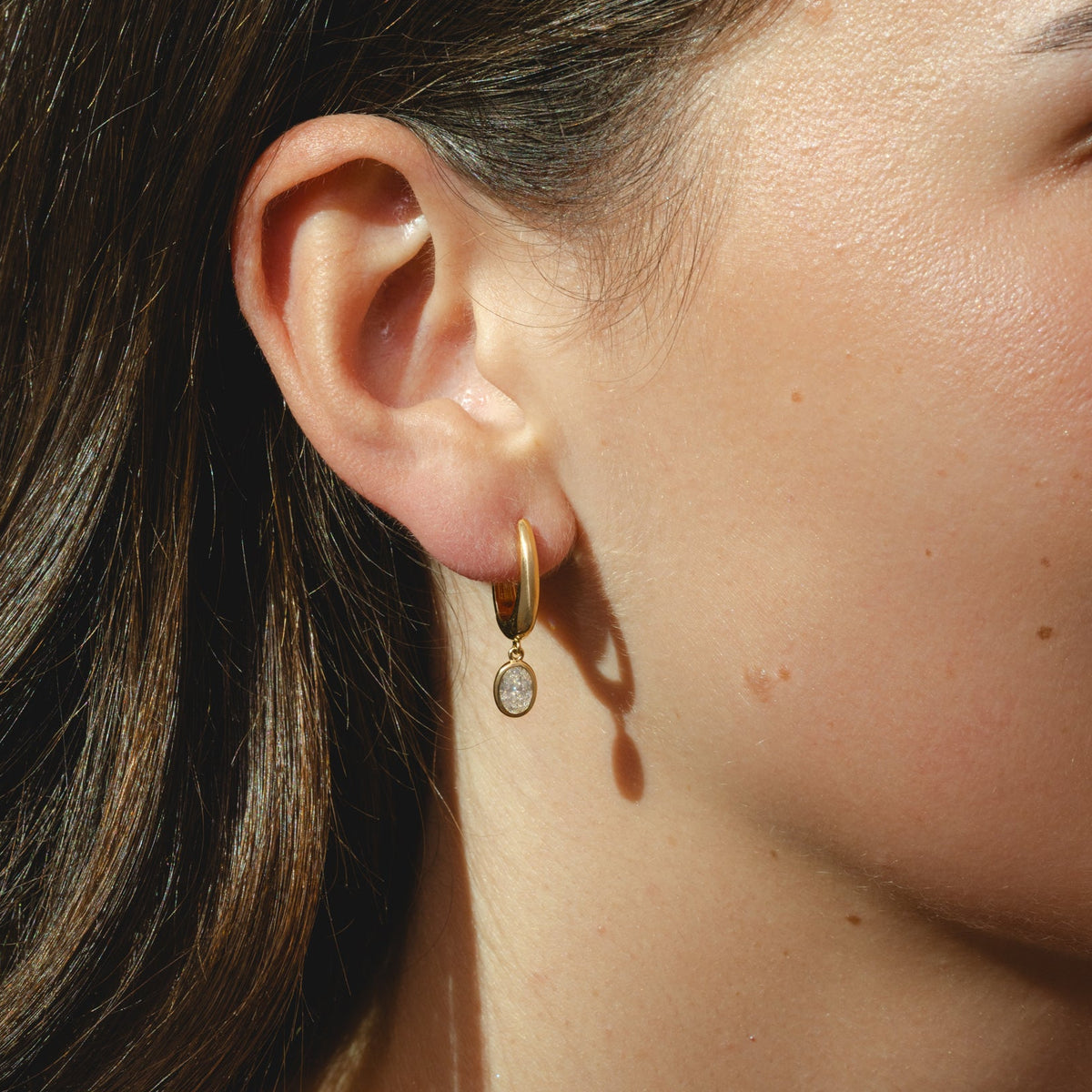gold hoop earrings with oval-cut 0.84ct diamonds in a bezel setting.