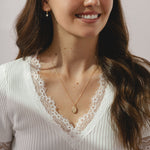 A gold locket pendant necklace on a delicate gold chain.