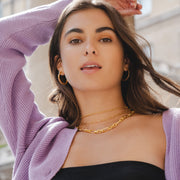 Model wears three yellow gold chunky chains layered